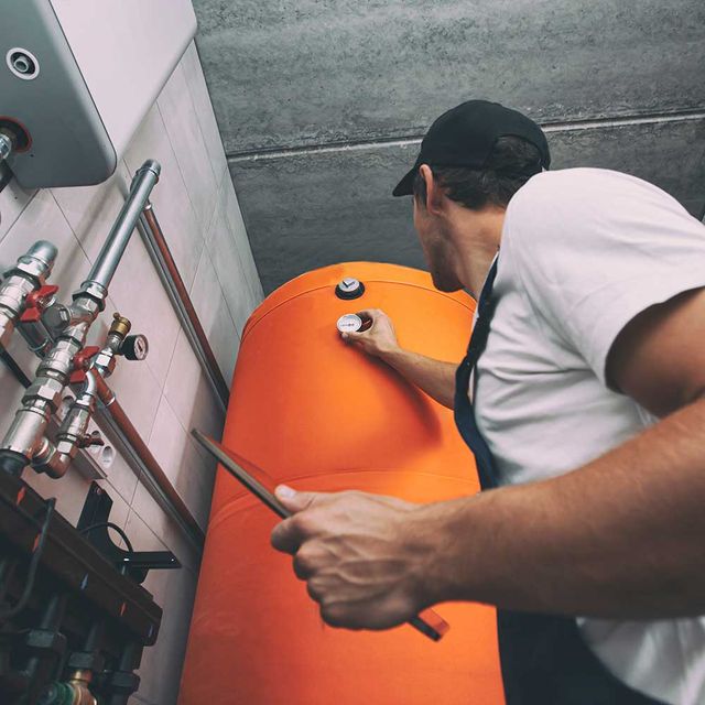 The technician checking the heating system in the boiler room with tablet in hand